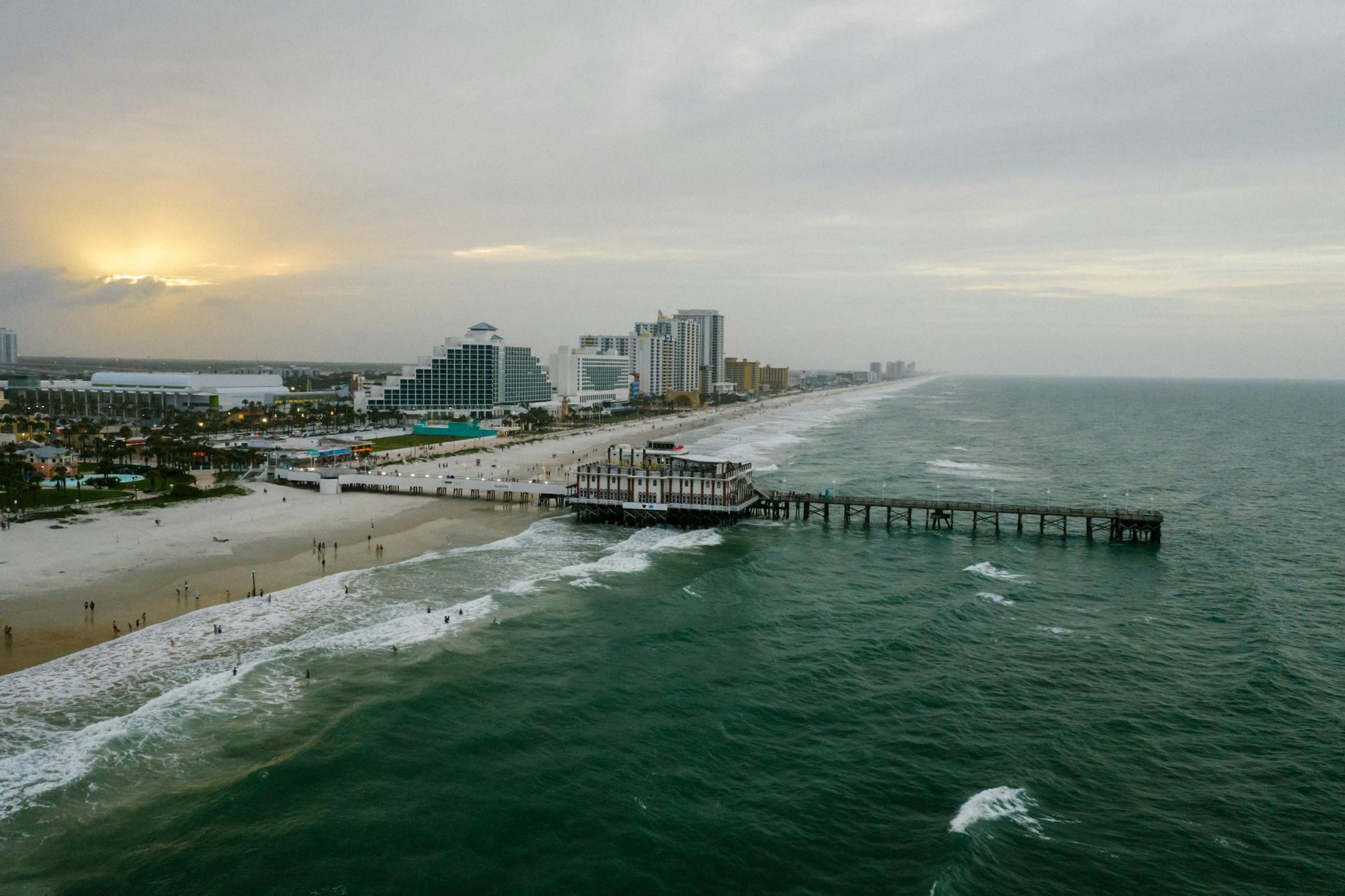 Aerial view of the Daytona Beach pier and Atlantic coastline in Volusia County, Florida, with brilliant blue ocean and white sand beach